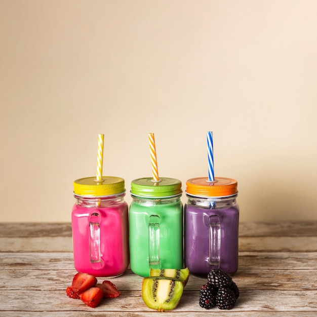 Vista frontal smoothies coloridos em frascos com frutas