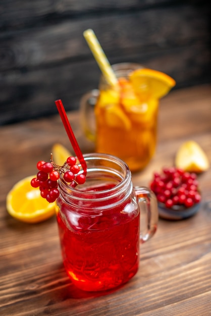 Vista frontal, suco de frutas frescas, bebidas de laranja e cranberry dentro de latas na mesa de madeira marrom.