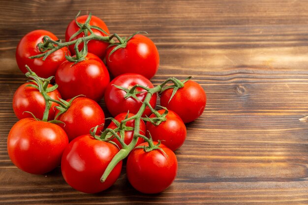Vista frontal, tomates vermelhos, vegetais maduros, em, marrom, madeira, mesa, vermelho, salada, vermelho, maduro, fresco, dieta