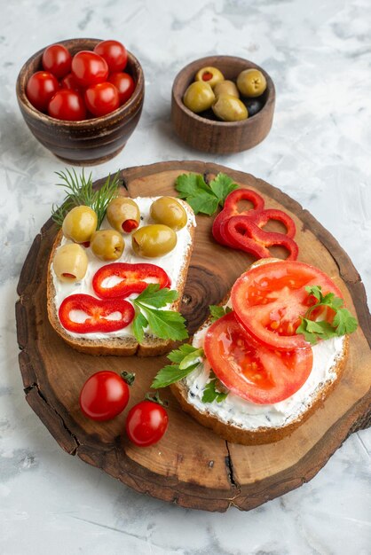 Vista frontal torradas saborosas com tomates e azeitonas na placa de madeira fundo branco almoço comida pão horizontal refeição jantar lanche sanduíche hambúrguer