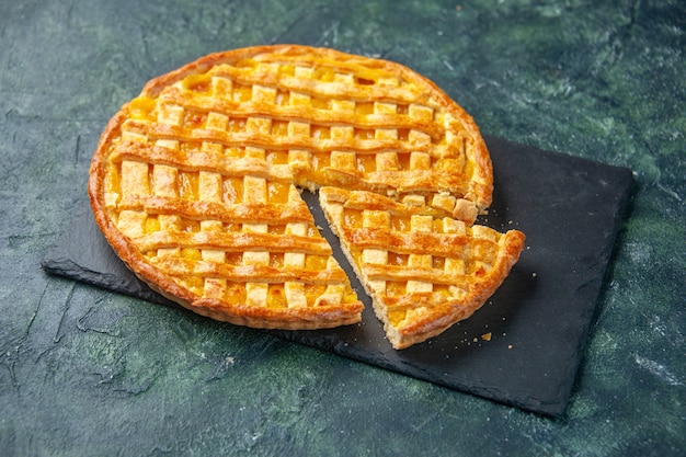 Vista frontal torta deliciosa de kumquat com um pedaço cortado em fundo escuro