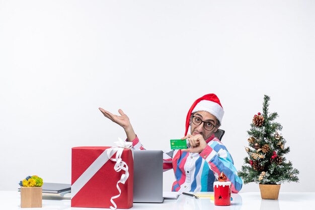 Foto grátis vista frontal, trabalhador masculino, sentado em seu local de trabalho, segurando o cartão do banco verde, trabalho, emoção, natal, escritório, dinheiro