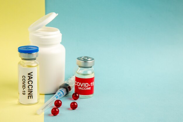 vista frontal vacinas de coronavírus com injeção em fundo amarelo-azul laboratório hospital vírus covid- ciência saúde pandemia cor droga grátis local