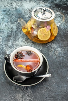 Vista frontal xícara de chá com limão e chaleira em fundo cinza cerimônia de café da manhã de frutas cor manhã de comida