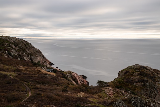 Vista hipnotizante de um oceano calmo cercado por montanhas rochosas em um dia nublado