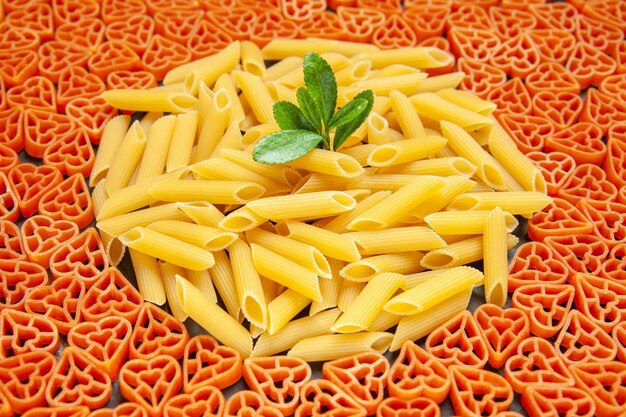 Vista inferior da massa italiana em forma de coração e penne em superfície escura