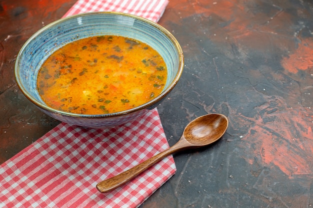 Foto grátis vista inferior da sopa de arroz em uma tigela no pano de cozinha quadriculado branco vermelho colher de pau no espaço livre da mesa