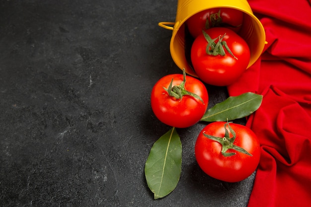 Vista inferior do balde com tomate vermelho e toalha vermelha em fundo escuro