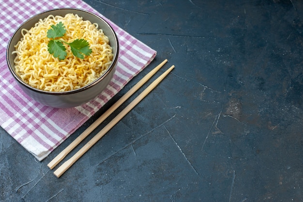 Foto grátis vista inferior do macarrão ramen em uma tigela em pauzinhos de toalha de cozinha xadrez branco rosa em mesa escura lugar livre