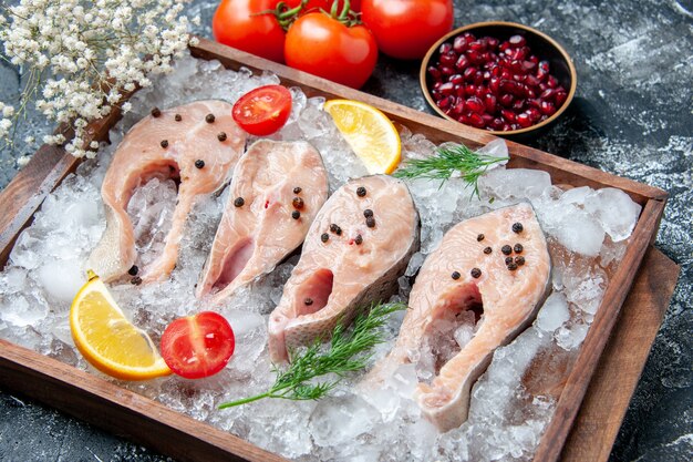 Vista inferior fatias de peixe cru com gelo em tabuleiro de madeira tigelas com sementes de romã tomates pequenas flores na mesa