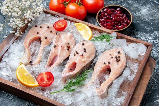Vista inferior fatias de peixe cru com gelo em tabuleiro de madeira tigelas com sementes de romã tomates pequenas flores na mesa