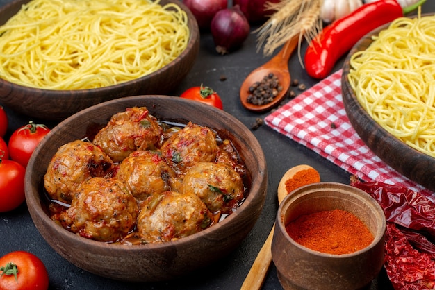 Vista inferior saborosa sopa de almôndegas em uma tigela de espaguete em uma tigela colheres de madeira tomates vermelhos na mesa