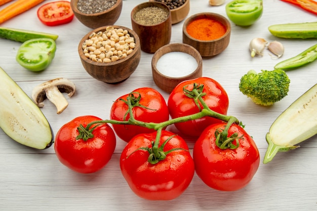 Vista inferior, tomates cortam legumes, feijões e especiarias em pequenas tigelas na mesa branca