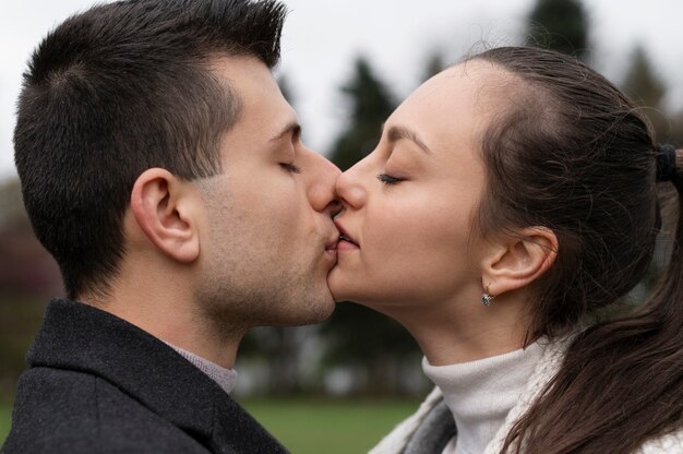 Vista lateral casal romântico beijando