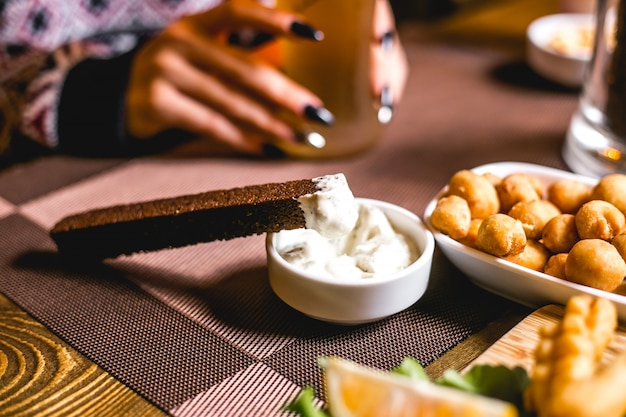 Vista lateral cerveja lanches crouton de pão integral com molho e ervilhas fritas