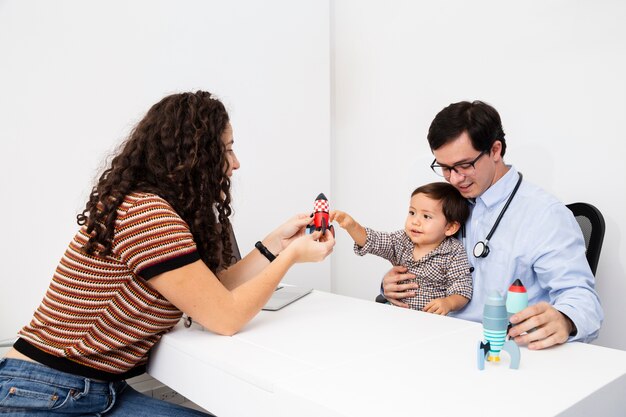 Vista lateral criança brincando com um brinquedo na visita de um médico