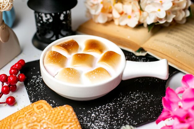 Vista lateral da caçarola de batata-doce tradicional prato de ação de Graças com marshmallows em formas repartidas sobre uma tábua de madeira preta