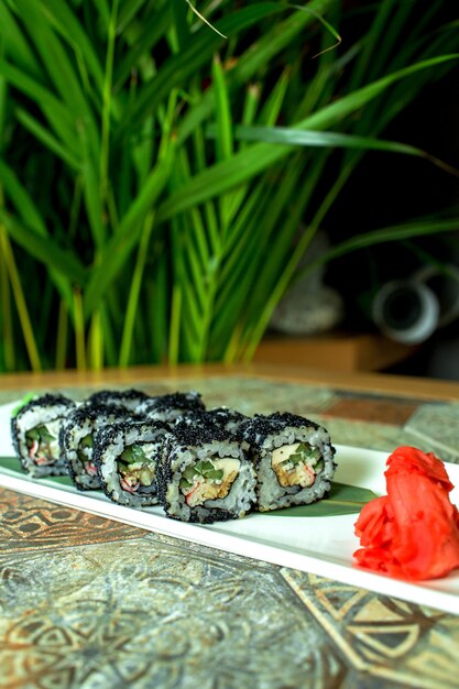 Vista lateral da cozinha japonesa tradicional preto sushi rolls com abacate de carne de caranguejo e cream cheese em verde