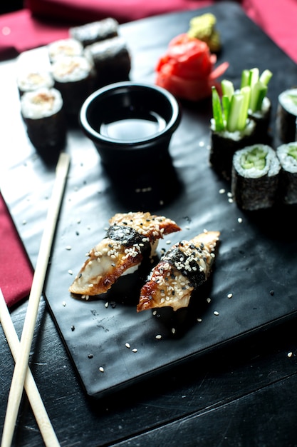 Vista lateral da cozinha japonesa tradicional unagi enguia nigiri sushi servido com molho de soja no quadro negro