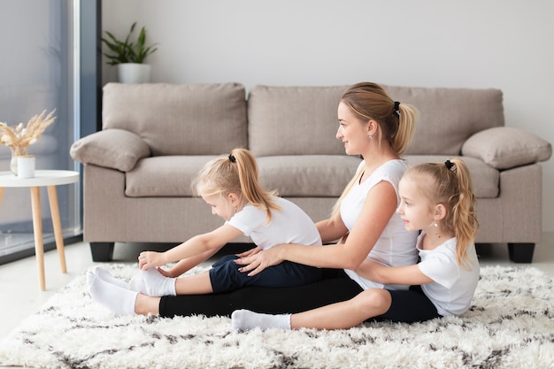 Vista lateral da família feliz de mãe e filhas em casa