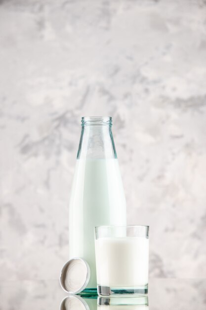 Vista lateral da garrafa de vidro aberta e copo com tampa de leite