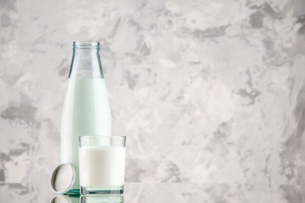 Vista lateral da garrafa de vidro e do copo com tampa de leite no lado direito em um fundo de cores pastel com espaço livre