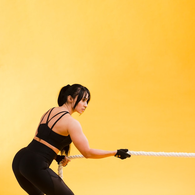 Vista lateral da mulher atlética, puxando a corda