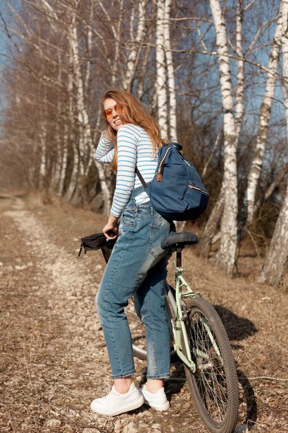 Vista lateral da mulher com bicicleta posando na natureza