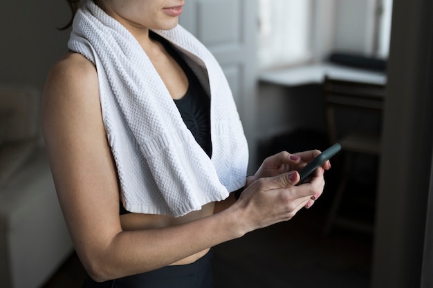 Vista lateral da mulher com uma toalha sobre os ombros usando smartwatch