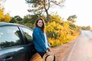 Foto grátis vista lateral da mulher posando ao ar livre ao lado do carro