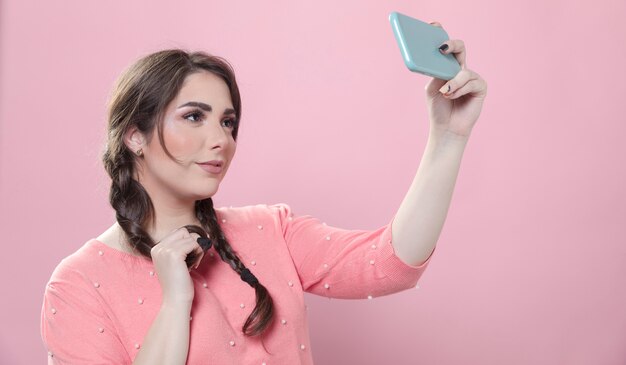 Vista lateral da mulher posando para uma selfie enquanto segura o smartphone