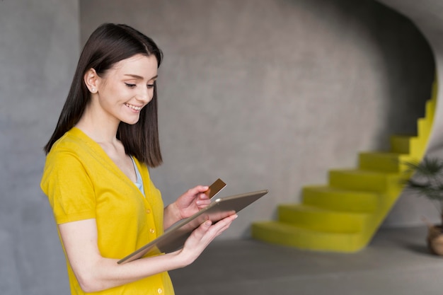 Foto grátis vista lateral da mulher segurando o tablet e cartão de crédito