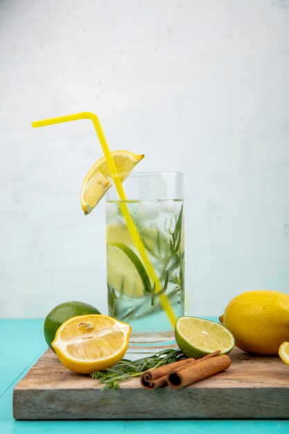 Vista lateral da refrescante água desintoxicante de verão com limão amarelo sobre branco