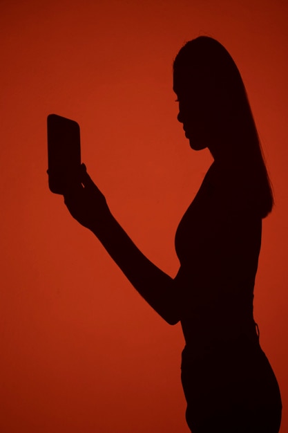 Vista lateral da sombra da mulher segurando o smartphone