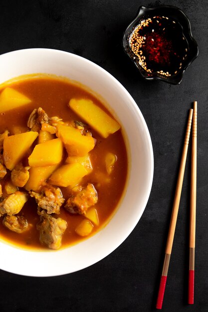 Vista lateral da sopa chinesa com frango e batatas no prato