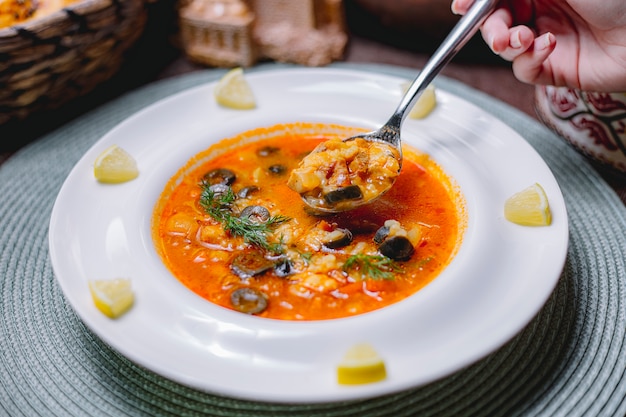 Vista lateral da sopa de legumes decorada com azeitonas pretas e endro em um prato