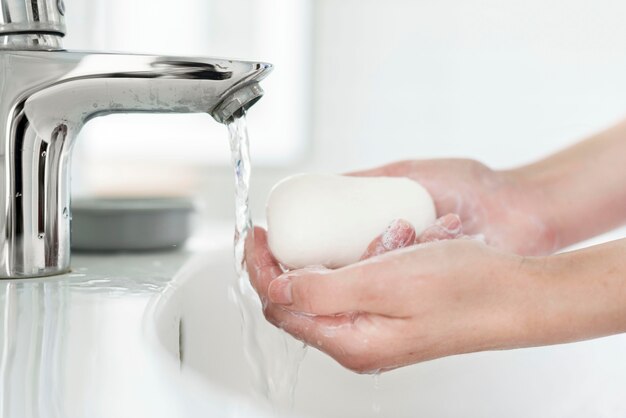Vista lateral das mãos lavando com sabonete na pia
