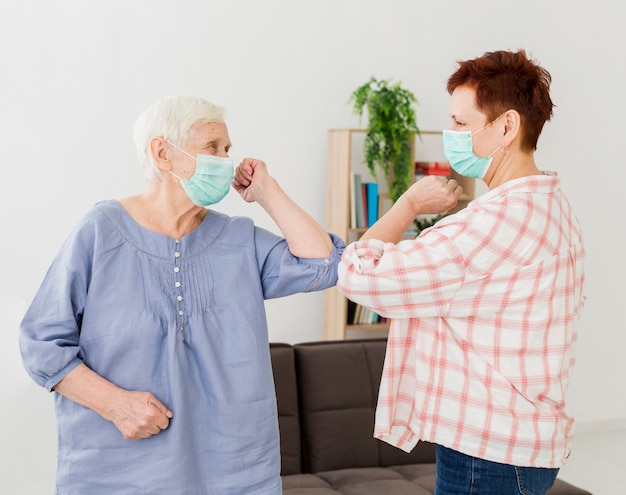 Vista lateral das mulheres mais velhas, cumprimentando-se em casa