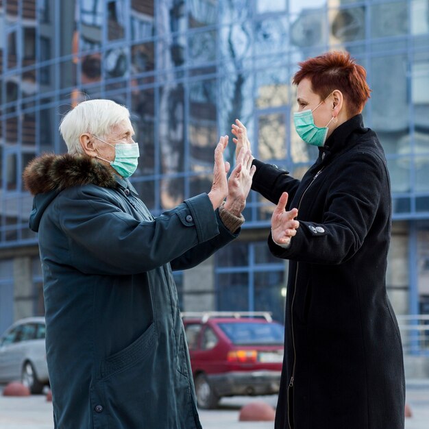 Vista lateral das mulheres mais velhas cumprimentando uns aos outros na cidade