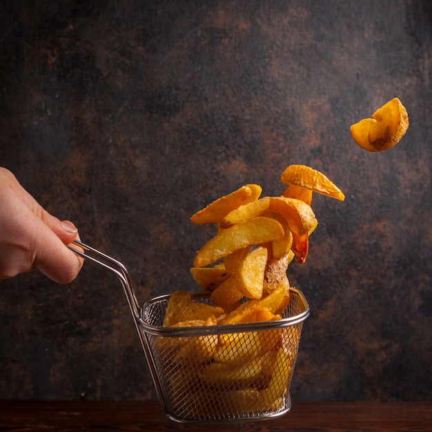 Foto grátis vista lateral de batatas fritas com mão humana na grelha para fritar