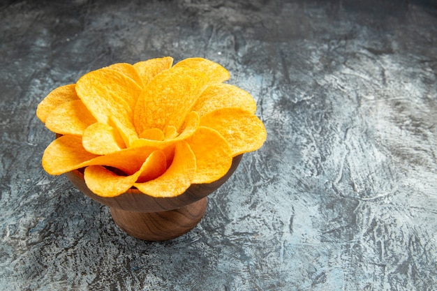 Vista lateral de batatas fritas decoradas em forma de flor em uma tigela marrom na mesa cinza