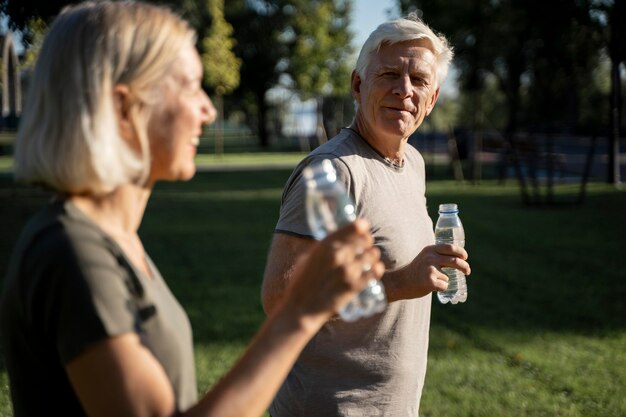 Vista lateral de casal bebendo água ao ar livre