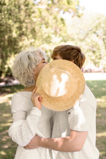 Foto grátis vista lateral de casal se beijando sob o chapéu ao ar livre