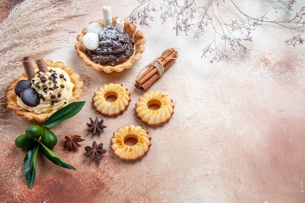 Vista lateral de close-up doces biscoitos cupcakes frutas cítricas em pau de canela