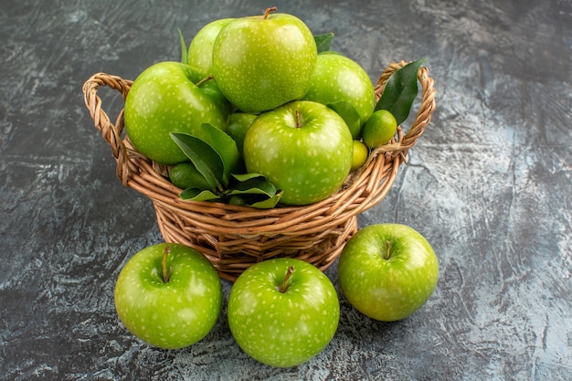 Vista lateral de close-up maçãs maçãs verdes com folhas de frutas cítricas na cesta