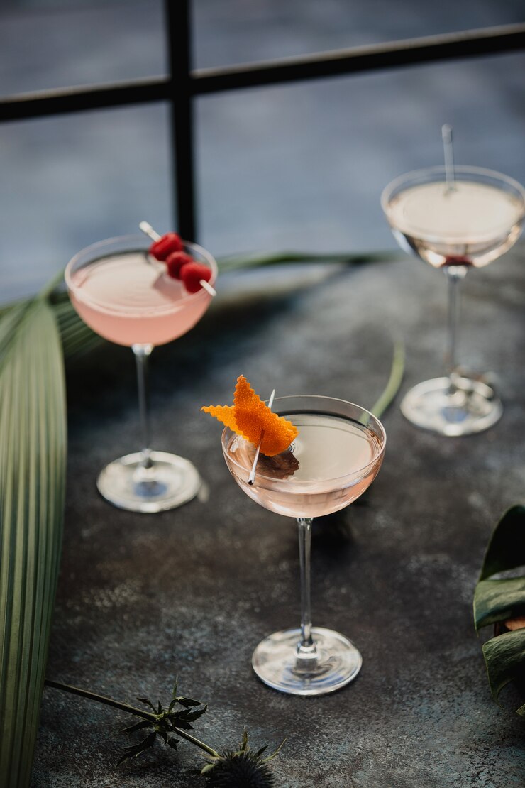 Foto grátis vista lateral de cocktails rosa decorados com frutas em um copo em cima da mesa