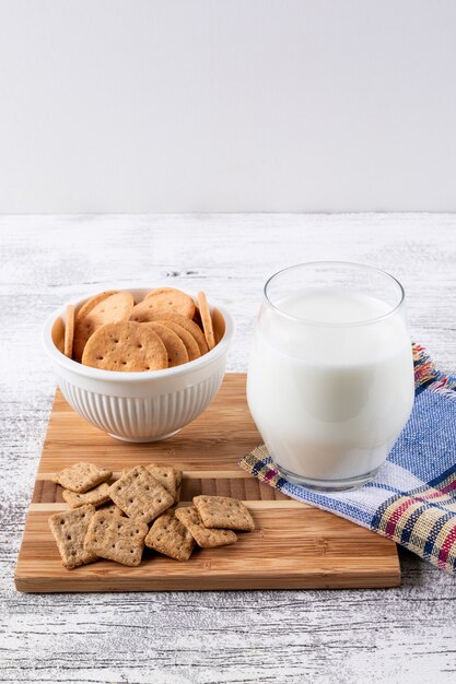 Vista lateral de cookies com leite na mesa de madeira vertical