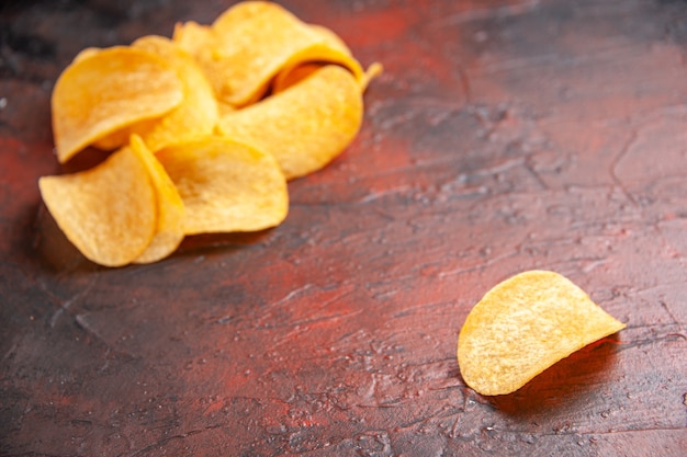 Vista lateral de deliciosas batatas fritas caseiras alinhadas em um fundo escuro.