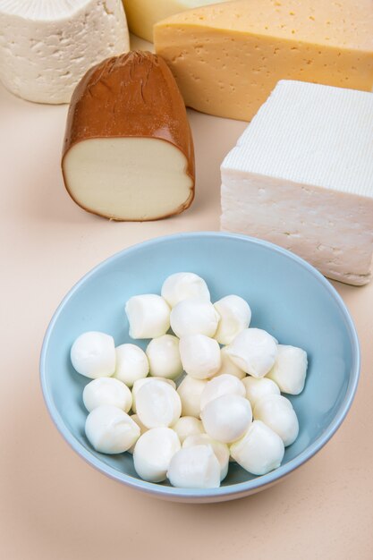 Vista lateral de diferentes tipos de queijo na mesa branca