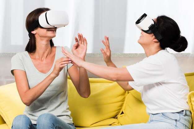 Foto grátis vista lateral de dois amigos em casa usando fone de ouvido de realidade virtual